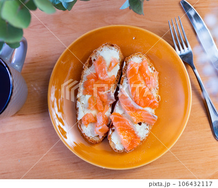On table there is plate with homemade light snack - toast, crispy salmon sandwiches 106432117