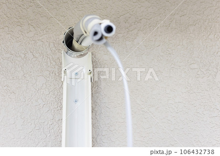 壁から飛び出したエアコンの配管と取付け中の化粧カバー　エアコン取り付け工事 106432738