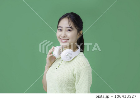 グリーンバックのヘッドフォンを首にかける若い女性 グリーンバックのヘッドフォンを首にかける若い女性 106433527