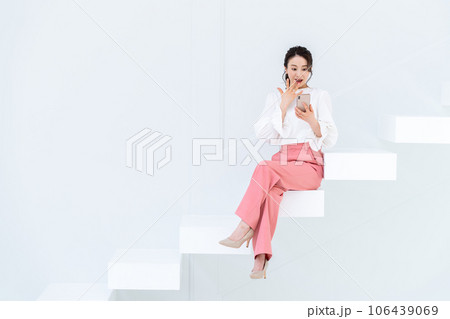階段で座ってスマホを見る若い女性 106439069