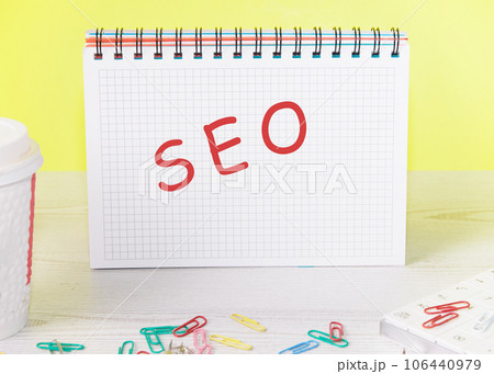 Seo the word is written on a blank sheet in a notebook standing on a table on a yellow background 106440979