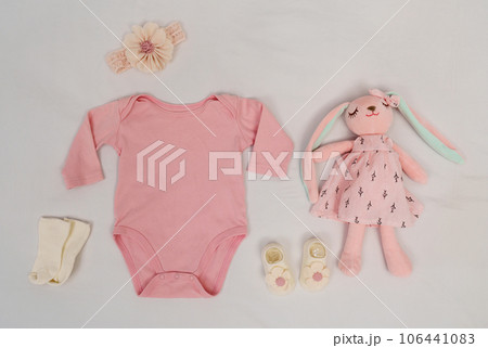 set of baby clothes and toy and accessories on white bed 106441083