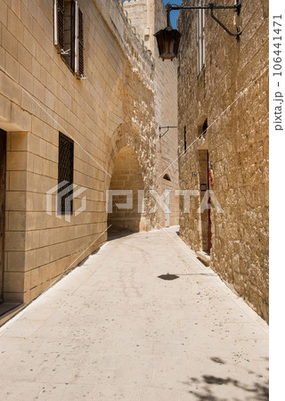 Narrow medieval street with stone houses in Mdina, Malta 106441471