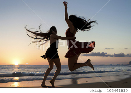 夕暮れの海でジャンプする2人の女性 106441639