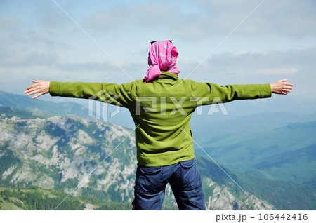 Hiker standing on the top of the mountain with raised hands Hiker standing on the top of the mountain with raised hands 106442416