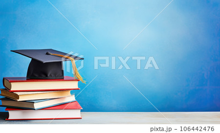 School books and graduation hat on table with blue wall background School books and graduation hat on table with blue wall background 106442476