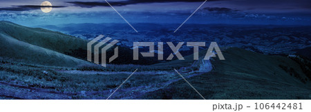 panoramic mountain landscape at night. winding trail path through the meadow down the hill. wonderful distant countryside scenery in full moon light 106442481