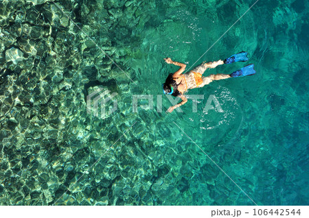 Young woman in swimsuit snorkeling in clear shallow tropical sea over coral reefs 106442544