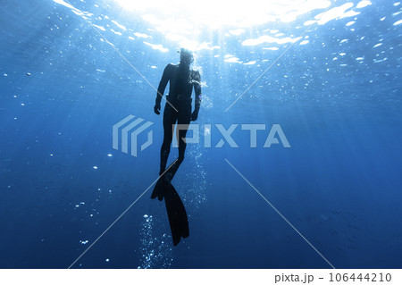 Freediver Swimming in Deep Sea With Sunrays. Freediver Swimming in Deep Sea With Sunrays. 106444210