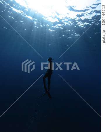 Freediver Swimming in Deep Sea With Sunrays. 106444212
