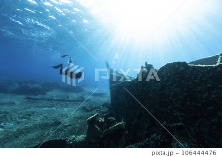 Freediver Swimming in Deep Sea and Exploring Ship Wreck. 106444476