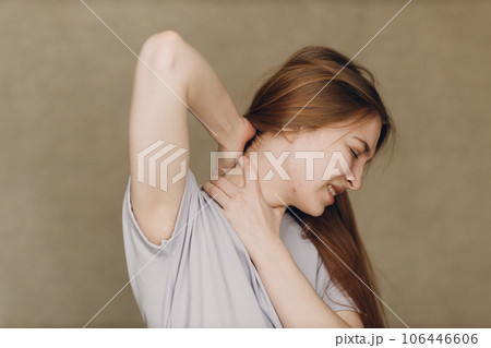 Young woman with upper neck pain ache against brown background Young woman with upper neck pain ache against brown background 106446606