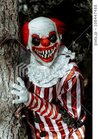 mad evil clown pops out of a tree in the woods 106447488