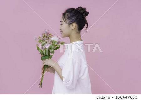 ピンクバックの花束を持つ若い女性のポートレート 106447653