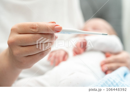 Mother evaluates newborn's health with a thermometer, Concept of infant care and safety Mother evaluates newborn's health with a thermometer, Concept of infant care and safety 106448392