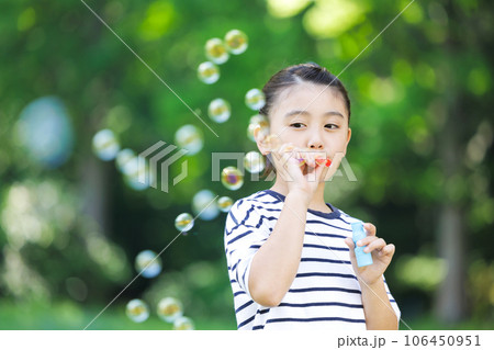 シャボン玉で遊ぶ小学生の女の子 106450951