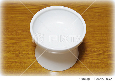 キャットフード用の白い器を木目のテーブルに置いた状態（イラスト風） 106451032
