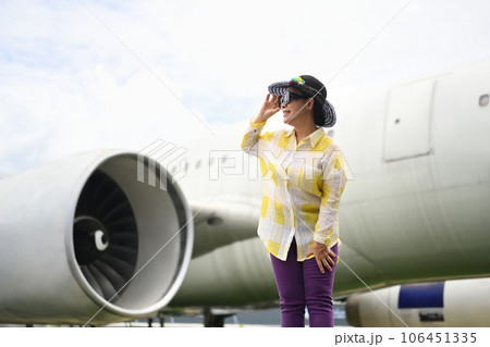 Active 60s woman in summer clothing and sunglasses walking on runway near airplane. Travel and summer vacation concept Active 60s woman in summer clothing and sunglasses walking on runway near airplane. Travel and summer vacation concept 106451335