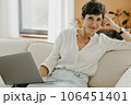 Portrait of middle aged woman sitting on couch with laptop. 106451401