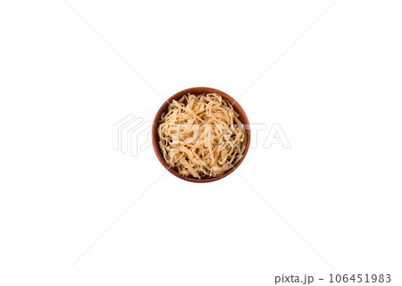 Delicious dried squid in the form of shavings with salt and spices on a ceramic plate 106451983