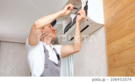 Repairman scrolls screws with screwdriver of air conditioner 106452074