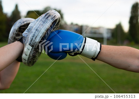 Hitting an old boxing glove on a boxing paw wrapped in duct tape for durability outdoors during outdoor boxing training 106455313