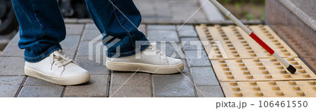 Close-up of female foot, walking stick and tactile tiles. Widescreen.  106461550