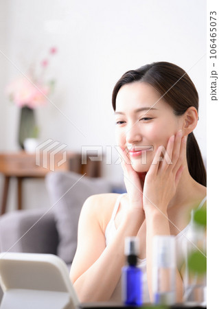 化粧水でお肌のお手入れをする美しい女性の写真 縦	 106465073