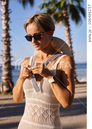 Young woman in summer knitted dress looking at camera near log on beach. 106466257