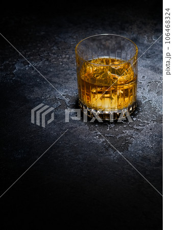 Whiskey glass with ice cubes in middle of black background.Macro Whiskey glass with ice cubes in middle of black background.Macro 106468324