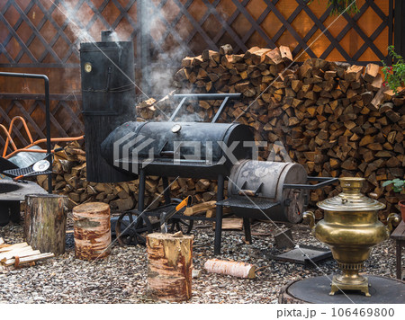 Big iron smokehouse with firewood stands on the courtyard. On the smokehouse, you can smoke various healthy foods. Small business smoking concept. 106469800