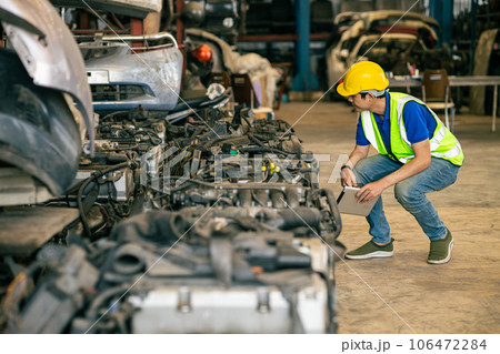 Engineer male worker check inventory store old used auto spare part engine gear part list for sale recycle in repair car garage market 106472284