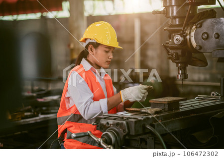 woman worker hard work focus working in heavy metal machine lathe milling factory industry 106472302