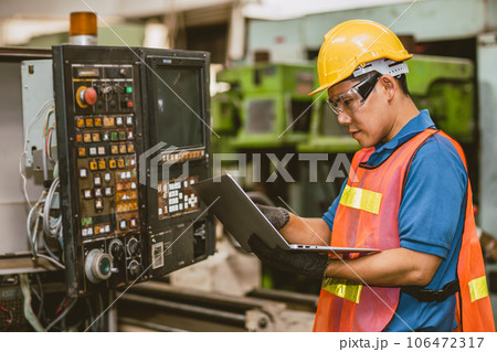 Engineer worker check service panel program operate CNC lathe machine with laptop computer fix repair old machine. Engineer worker check service panel program operate CNC lathe machine with laptop computer fix repair old machine. 106472317