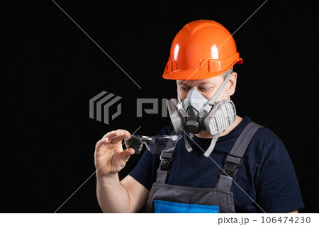 A man wearing a helmet, respirator and goggles on a black background 106474230