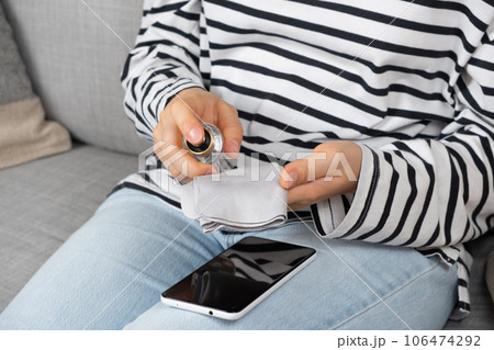 A woman cleans the screen of a smartphone with a special liquid using a napkin. A woman cleans the screen of a smartphone with a special liquid using a napkin. 106474292