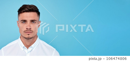 Portrait of a man with short brown hair. Closeup face of a serious Caucasian adult guy on a blue background looking at the camera.  Emotionless European grown up man in a blue shirt. 106474806