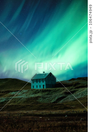 Northern lights glowing over abandoned house on hill in remote location at Iceland 106474949