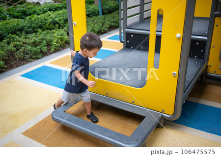 A toddler is playing on toys in the park 106475575