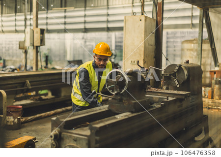 Hispanic Latin Indian male professional tecnician worker working with steel precision milling machine in lathe metal factory Hispanic Latin Indian male professional tecnician worker working with steel precision milling machine in lathe metal factory 106476358