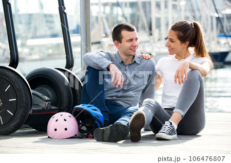 Couple sitting near segways at sea front 106476807