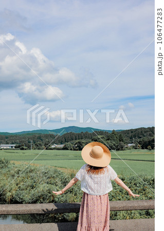 真夏に田舎風景を眺める麦わら帽子を被った少女の写真素材 [106477283