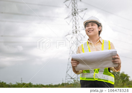 Happy engineer woman happy smiling with high voltages electricity transmission pole building project on background 106478328