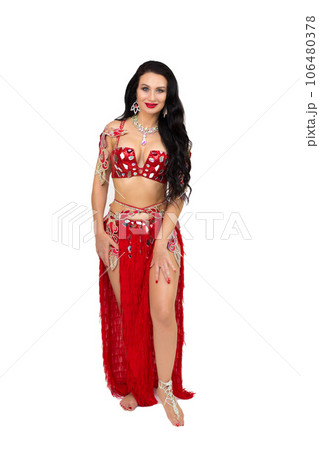 A brunette girl in a red dance costume performs oriental dances, a gray background A brunette girl in a red dance costume performs oriental dances, a gray background 106480378
