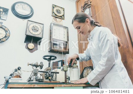 Woman watchmaker cleaning clockwork of a watch 106481481