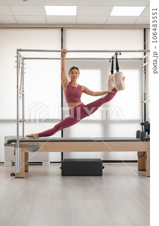 Beautiful asian woman doing splits on a reformer.  106483551