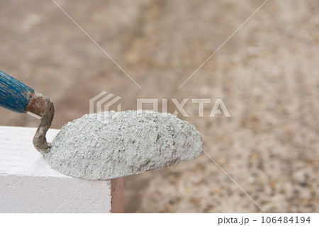 Cement powder or mortar with trowel put on the Lightweight Concrete brick for construction work.. Cement powder or mortar with trowel put on the Lightweight Concrete brick for construction work.. 106484194
