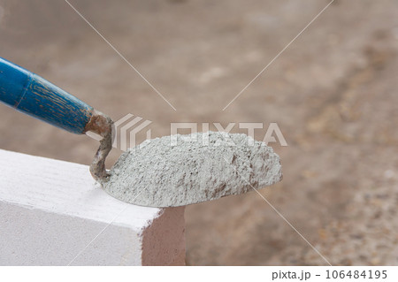 Cement powder or mortar with trowel put on the Lightweight Concrete brick for construction work.. Cement powder or mortar with trowel put on the Lightweight Concrete brick for construction work.. 106484195