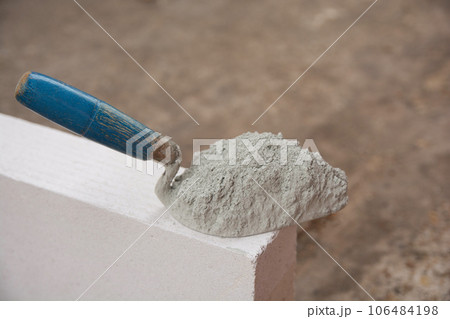 Cement powder or mortar with trowel put on the Lightweight Concrete brick for construction work.. Cement powder or mortar with trowel put on the Lightweight Concrete brick for construction work.. 106484198