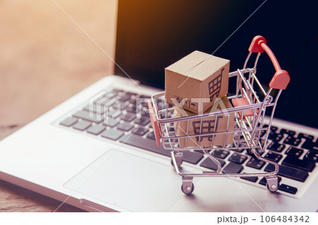 Shopping online concept - Parcel or Paper cartons with a shopping cart logo in a trolley on a laptop keyboard. Shopping service on The online web. offers home delivery.. Shopping online concept - Parcel or Paper cartons with a shopping cart logo in a trolley on a laptop keyboard. Shopping service on The online web. offers home delivery.. 106484342